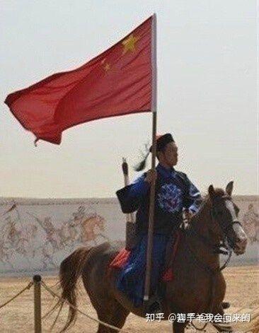 这是一张经过P图改编的合成图像，图中一位身着清朝武官传统服饰的真人骑在马上，手中却持有一面中华人民共和国国旗，形成了强烈的时代错位反差，制造出荒诞搞笑的视觉效果，属于旧图再创作的趣味P图。