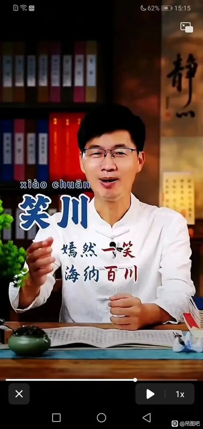 这是一张经过P图改编的竖屏视频截图，原图呈现的是一位身着白色中式服装的国学类知识博主在桌前讲解的场景：桌上摆放着翻开的古籍样式书籍、茶宠等物品，左侧有绿植点缀，背景是摆满书籍的书架与书法装饰，整体风格偏向传统文化科普。图片被网友进行玩梗修改，添加了蓝色的拼音“xiào chuān”和醒目大字“笑川”，以及“嫣然一笑 海纳百川”的文字，将博主形象与网络抽象文化中的知名人物“孙笑川（带带大师兄）”结合，利用名字创作了贴合的文字标语，属于网络抽象文化的二次创作，右下角带有“吊图吧”的水印，表明该图的传播平台。