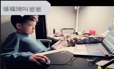 这是一张网络趣味梗图，画面主体是一名身穿浅蓝色毛衣的小男孩坐在室内书桌前，右手握着鼠标，神情严肃专注地看向面前摆放的笔记本电脑，书桌后方的区域还摆放着Switch游戏机、床铺、小摆件等居家物品。图片左上角有一个白色对话气泡，内有文字“骚福瑞叫爸爸”，其中“骚福瑞”是苹果自带浏览器Safari的中文谐音，属于谐音玩梗内容，整体笑点来自谐音错位的趣味感。