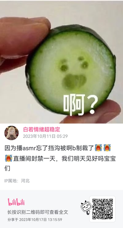 图片上半部分为特写镜头：一只手捏着一片新鲜黄瓜切片，其横截面的天然纹理恰好形成了一双圆眼睛和一个张大的嘴巴，酷似一张惊讶的人脸。切片下方叠加白色文字“啊?”，与黄瓜的“表情”形成趣味呼应。下半部分是Bilibili用户“白若情绪超稳定”的动态截图，发布于2023年10月11日05:29，内容提到因直播ASMR时“忘挡沟”被平台制裁，直播间封禁一天，并向观众告别“我们明天见好吗宝宝们”，配文后附有三个哭泣表情符号。整体画面将自然形成的趣味图案与网络直播常见的违规封禁事件结合，兼具幽默感与真实感。