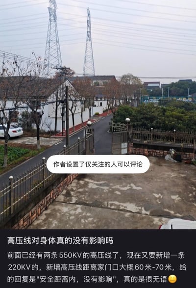 图片展示了一条宁静的居民街道场景，街道两旁有白色房屋、树木和停放的车辆，背景中矗立着两座高大的高压线塔。图片底部配有文字，表达了对家门口新增高压线的健康担忧：现有两条550KV高压线，拟新增一条220KV高压线，距离家门口60-70米，官方回复称在安全距离内无影响，但发布者对此表示无奈。