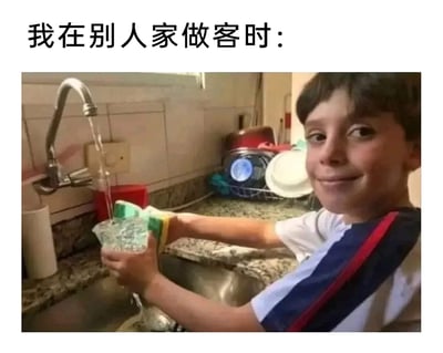 这是一张图文结合的趣味梗图，上方配有文字“我在别人家做客时：”，下方是一张真实的生活场景照片。照片中的男孩穿着白蓝红相间的短袖，面带乖巧的微笑，双手拿着杯子和海绵，做出在厨房水槽边清洗杯子的动作，但水龙头流出的水完全没有进入杯子，直接淌进了水槽之中。这一画面生动地调侃了很多人在别人家做客时，为了表现得懂事勤快，刻意做出帮忙的样子，实则只是做表面功夫的日常社交小细节，充满了生活气息和幽默趣味，能引发很多人的共鸣。