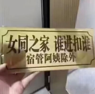 这是一块被手拿着的宿舍趣味标语牌，主标语写着“女同之家 谁进扣谁”，下方补充“宿管阿姨除外”。用夸张搞笑的口吻模仿“禁地”警告，调侃女生宿舍的私密感，“扣谁”的说法俏皮又硬核，特意排除宿管阿姨的补充，充满学生宿舍的整活趣味，没有双关或谐音梗。