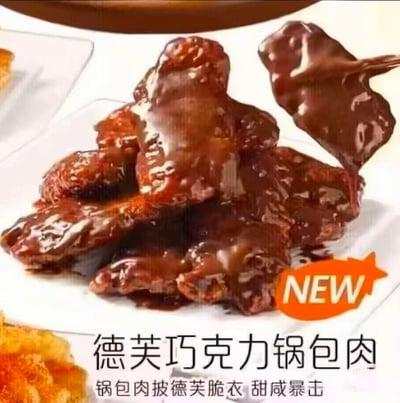 这是一张网友自制的恶搞美食宣传图，画面主体是裹着浓郁德芙巧克力酱的锅包肉，右侧有一块被叉子叉起的巧克力锅包肉，右下角的橙色标识标注“NEW”，下方配有文字“德芙巧克力锅包肉”和“锅包肉披德芙脆衣 甜咸暴击”。将中式经典酸甜口的锅包肉与丝滑甜腻的德芙巧克力结合，打造出反差感强烈的黑暗料理创意，视觉冲击感十足，用甜咸混搭的新奇设定制造搞笑猎奇的效果。