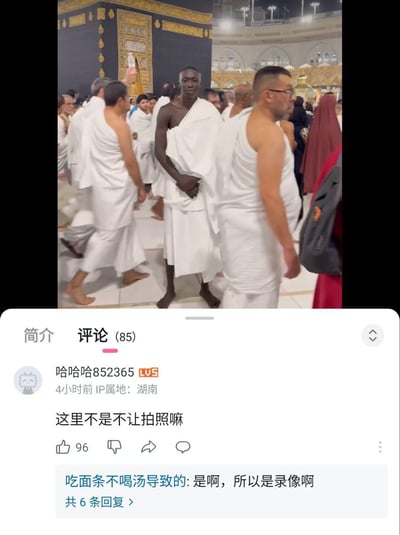 这是一张B站视频的截图，上半部分是拍摄于伊斯兰教圣地麦加禁寺的画面，身着戒衣的穆斯林朝圣者正在围绕天房（克尔白）进行宗教仪式；下半部分是该视频的评论区，用户“哈哈哈852365”留言提问“这里不是不让拍照嘛”，另一位用户回复“是啊，所以是录像啊”，用玩文字游戏的方式抖机灵，制造出戏谑搞笑的效果，利用“拍照”和“录像”的概念差异来调侃拍摄行为。