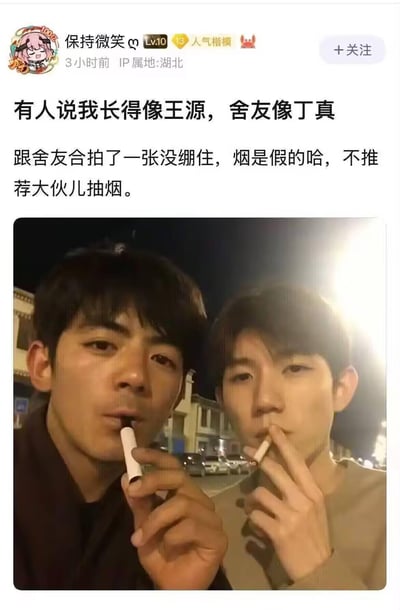 这是一张社交平台的发帖截图，发帖人自称被说长得像王源，舍友像丁真，于是发布了一张合成的、模仿两人形象抽烟的合拍图，并特意标注烟是假的，不推荐抽烟，以撞脸明星的方式玩梗，同时做出了健康引导，整体风格轻松搞笑。