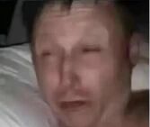 图片为一名男子的面部特写，表情呈现明显的痛苦与疲惫感，眉头紧锁，眼睛半睁，面部肌肉紧绷。背景模糊，推测为室内环境，光线较暗，整体色调偏沉，突出人物的负面情绪状态。
