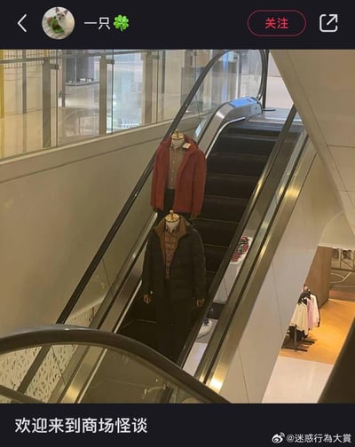 这是一张商场内的实拍图，两个仅保留上半身与头部模型的服装模特被放置在自动扶梯上，因缺少下半身，视觉上仿佛“悬浮”在扶梯台阶上，搭配下方配文「欢迎来到商场怪谈」，利用视觉错位营造出类似都市传说的诡异氛围，场景迷惑又好笑，像是商场里发生的怪异事件，成为社交媒体上的搞笑迷惑内容。