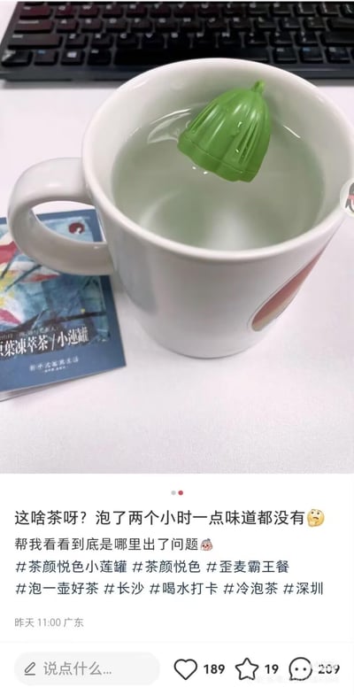 这是一则社交平台的生活趣事分享截图，上方是用户实拍场景：白色马克杯中泡着茶颜悦色小莲罐的绿色外盖，杯子下压着小莲罐的宣传卡片，背景可见键盘；下方是用户配文：“这啥茶呀？泡了两个小时一点味道都没有😮‍💨 帮我看看到底是哪里出了问题🥺”，还附带#茶颜悦色小莲罐 #茶颜悦色等相关话题。用户误将小莲罐的外盖当作茶包冲泡，自然泡不出茶味，是一个搞笑的生活小乌龙。