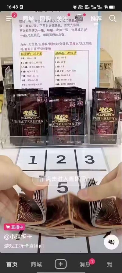 这是一张抖音平台的直播截图，展示的是@小晴拆卡的游戏王拆卡直播间。画面上方清晰列出了拆卡的规则、可许愿的游戏王角色，以及标准版29.9元和进阶版49.9元两个档位的拆卡套餐奖励，不同的碰牌次数对应不同稀有度、数量的游戏王卡包；画面中间的透明展示架上摆放着多包游戏王RA RARITY COLLECTION系列卡包；画面下方是主播的双手拿着一叠游戏王卡牌，正在进行拆卡操作，画面中间有“点击进入直播间”的引导提示；底部显示直播间账号信息、“直播中”标识以及抖音的首页、商城等底部导航栏，整体是典型的线上卡牌拆卡直播的引流画面，面向游戏王卡牌收藏爱好者，通过不同档位的奖励吸引用户参与拆卡。