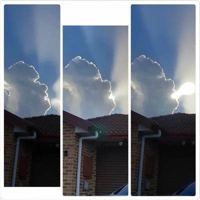 这是由三张连续抓拍的照片左右拼接组成的静态图，画面下半部分是红砖民居的屋顶、檐下排水管等建筑结构，上半部分是晴朗蓝天与大朵积云，云朵的轮廓恰好和手持手枪的侧影高度相似。三张图按时间顺序排布，展示了太阳从云朵后方逐渐移动到云朵“手枪”轮廓枪口位置的全过程，最终呈现出云朵手枪正“开枪射击”、子弹是太阳的巧合趣味效果，属于天然形成的视觉错位场景。