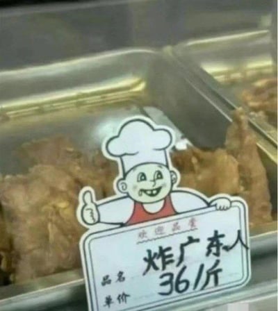 这是一张经过P图改编的美食档口照片，画面里的金属餐盒中装着炸制的食物，餐盒上方立着一个卡通厨师造型的标价牌。标价牌上写着“欢迎品尝”，品名被修改为“炸广东人”，单价标注36/斤。这是利用谐音梗制造的笑点，实际对应的应该是潮汕特色小吃“炸广章”，通过将“广章”谐音成“广东人”，营造出荒诞搞笑的效果。