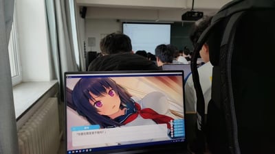 在严肃的大学课堂环境中，前排的笔记本电脑却在运行美少女视觉小说游戏，游戏角色美咲说出「你要在教室里干我吗？」的台词，与周围认真上课的氛围形成强烈反差，营造出一种上课摸鱼即将社死的搞笑又尴尬的氛围。