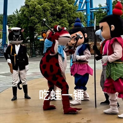 图片展示了游乐园中的多个吉祥物角色互动场景。左侧有身着黑色警服、戴着猫耳头套的“黑猫警长”角色，双手叉腰站立；中间是一只红色带黑色斑点的“青蛙精”造型吉祥物，手持锤子做出挥击姿态，正对着前方一位蓝帽蓝衣、手持长矛的“葫芦娃（二娃）”角色；右侧还有一位穿粉色上衣、绿色叶子裙的“葫芦娃（大娃）”角色。背景可见游乐园的蓝色过山车轨道和绿树。图片底部有白色文字“吃蛙一锤”，结合角色动作形成趣味战斗场景，模仿经典动画桥段制造欢乐氛围。