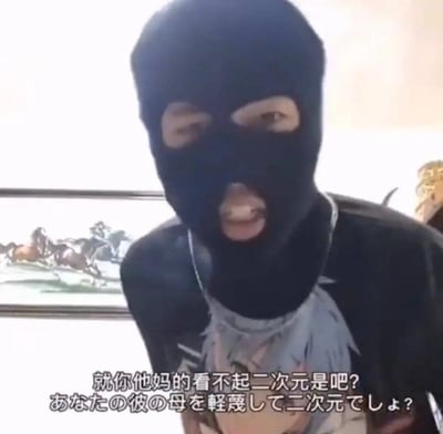 图中是一位戴着黑色劫匪头套的真人男子，身穿印有二次元角色的黑色T恤，身体前倾，嘴巴大张，表情愤怒激动，似乎在激烈指责。画面下方配有中文台词“就你他妈的看不起二次元是吧？”，还有一句机翻风格的日文“あなたの彼の母を軽蔑して二次元でしょ？”，通过凶悍的外在造型和维护二次元的内容形成强烈反差，制造搞笑效果，常被用来表达二次元爱好者对被偏见对待的不满，或是作为玩梗整活的表情包使用。
