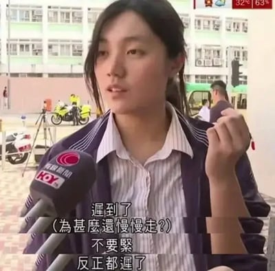 图片为一段采访场景截图，画面中一名穿着条纹衬衫和深色外套的人正手持麦克风接受采访，背景有建筑物和摩托车。图中字幕显示：“遲到了（為甚麼還慢慢走？）不要緊反正都遲了”，展现了一种面对迟到的摆烂心态，带有幽默和无奈的情绪。