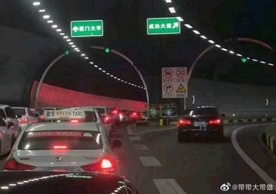 这是一张拍摄于厦门某隧道内的夜间路况照片，隧道顶部的照明灯带清晰照亮了上方的绿色道路指示牌，直行通往厦门大学的车道排满了车辆，所有车都亮着红色尾灯处于拥堵缓行状态，而右转通往成功大道的车道几乎没有车辆通行十分顺畅。该图被网友赋予隐喻含义，调侃大众挤破头走升学内卷的路径，却少有人选择直接通向“成功”的道路，成为传播度较高的网络梗图。