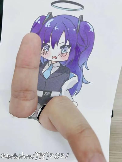 一张创意手绘作品，展示了一个紫色头发、带有猫耳和光环的动漫女孩形象。画面中通过巧妙的纸张剪裁和手指摆放，创造出手指穿透女孩身体的视觉错觉效果。女孩有着蓝色的眼睛和害羞的表情，脸颊带有红晕，穿着黑色背心和蓝色领带，胸前有数字"17"的标志。