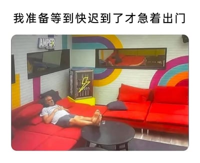 这是一张用来调侃职场拖延行为的梗图，上方配有文字“我准备等到快迟到了才急着出门”，图中主体是一位男士，他惬意地躺在色彩鲜艳的红色组合沙发上，双脚搭在黑色圆形茶几上，双手放在肚子上，神态放松，完全没有要起身行动的迹象。背景是带有彩色弧形装饰的室内空间，左上角有“AMPER”标识，整体画面将“明明需要出门上班却拖延不动，非要等到快迟到才着急”的状态具象化，精准戳中不少职场人的日常状态，引发共鸣。