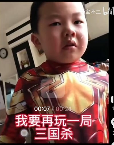 这是一段B站短视频的截图，画面中一个穿着漫威钢铁侠主题紧身衣的小朋友脸上挂着眼泪，一脸委屈难过的神情，画面下方配着醒目的红色文字“我要再玩一局三国杀”，视频进度条显示当前为00:07/00:24。超级英雄的酷炫装扮和小朋友因为不能继续玩桌游而哭闹的反差感，让画面充满了搞笑又可爱的氛围，真实展现了小朋友沉迷桌面游戏的日常趣事。