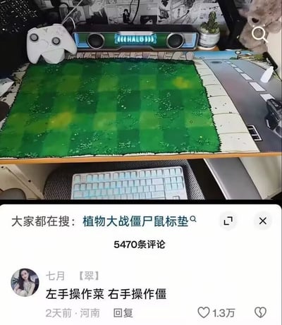这是一张社交媒体内容截图，上半部分展示了用户的桌面布置：桌面最显眼的位置铺有一块还原经典游戏《植物大战僵尸》中草坪格子样式的超大鼠标垫，鼠标垫旁摆放着白色游戏手柄、带发光字样的音响、小型多肉盆栽、灰色毛绒玩具等物品，桌面下方还露出白色键盘。下半部分是该内容的评论区，显示该内容关联搜索词为“植物大战僵尸鼠标垫”，共有5470条评论，其中用户“七月【翠】”发布的评论“左手操作菜 右手操作僵”巧用“植物大战僵尸”的谐音梗，“菜”对应“植物”，“僵”对应“僵尸”，趣味十足，该评论获得1.3万点赞。
