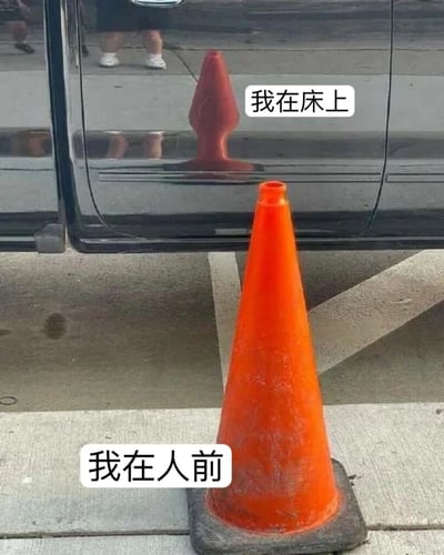 图片中前景有一个橙色交通锥，锥身前方配有文字“我在人前”；背景黑色汽车的车门反光处叠加了文字“我在床上”。通过交通锥直立的形态与“人前”状态对应，反光中隐含的“床上”状态形成幽默对比，调侃人们在公众场合与私人空间的不同生活状态。