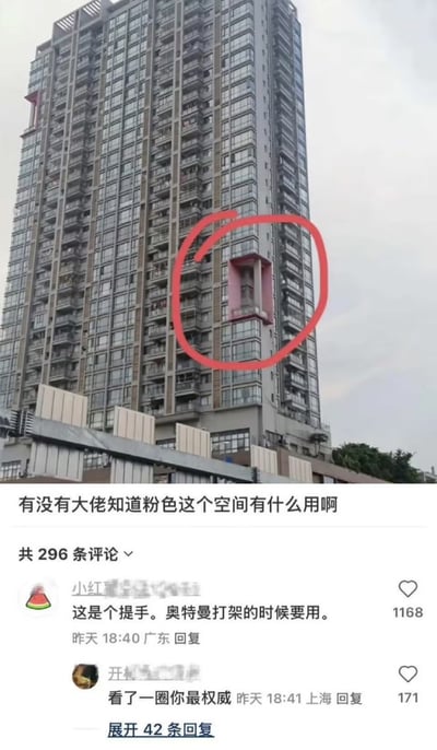 图片展示了一栋高层住宅楼，建筑外立面主要为玻璃幕墙结构。在建筑中部位置，有一个粉色的突出空间被红色圆圈重点标记出来。图片下方配有文字提问："有没有大佬知道粉色这个空间有什么用啊"，并显示有296条评论。其中一条高赞评论回答："这是个提手。奥特曼打架的时候要用。"，该评论获得了1168个点赞。