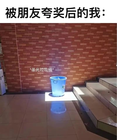 图片上方有文字'被朋友夸奖后的我：'，下方是一个蓝色垃圾桶被聚光灯照亮，并有文字标注'*圣光垃圾桶*'。这张梗图通过将被夸奖后的自己比喻为被神圣光芒照耀的垃圾桶，用反差制造幽默效果，表达了一种自嘲式的得意情绪。
