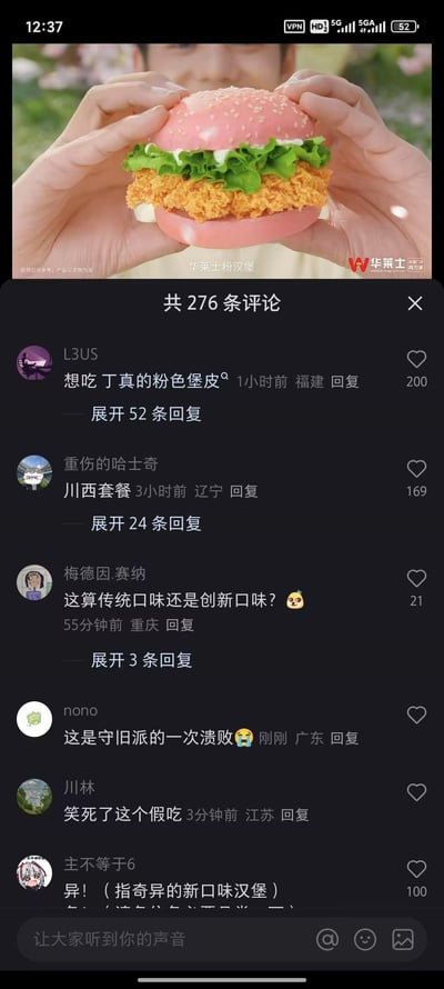 这是一张竖屏的短视频平台评论区截图，上方展示了华莱士推出的新品粉汉堡：粉色的汉堡胚夹着金黄炸鸡排、新鲜生菜与白色酱料，由一双手捧着呈现，画面标注有“华莱士粉汉堡”及“视频仅供参考，产品以实物为准”的提示，右下角是华莱士品牌标识。下方是该内容的评论区，共276条评论，高赞评论包括玩丁真相关梗的“想吃丁真的粉色堡皮”，结合川西背景玩梗的“川西套餐”，还有讨论口味、调侃广告假吃、评价新口味的内容，网友们围绕这款新奇的粉色汉堡展开趣味玩梗与讨论，氛围轻松搞笑。