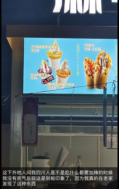 这是一张夜晚拍摄的街头冰淇淋门店显示屏实拍图，屏幕上展示了三款极具四川特色的辣味冰淇淋：干海椒香辣冰淇淋、红油辣椒冰淇淋、糊辣壳麻辣冰淇淋，单份售价均为10元，同时还有售价8-15元的鸡蛋仔产品。图片底部配有网友的吐槽文字：
> 这下外地人问我四川人是不是吃什么都要加辣的时候我没有底气反驳这是刻板印象了，因为我真的在老家发现了这种东西

这张图用打破常规的辣味冰淇淋，调侃了“四川人无辣不欢”的地域刻板印象，反差感拉满，让人觉得既新奇又好笑。