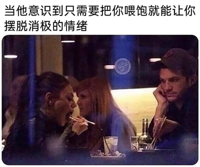 这是一张带文字的搞笑梗图，上方配文为“当他意识到只需要把你喂饱就能让你摆脱消极的情绪”。画面呈现的是餐厅内的场景，一位女生张大嘴巴，被身旁的人用筷子喂食；右侧的安德鲁·加菲尔德单手托着脸颊，另一只手拿着筷子，眼神带着无奈又宠溺的意味看向进食的女生，生动地诠释了在伴侣情绪低落时，用投喂这种简单直接的方式来哄人的相处模式，充满了生活化的趣味和温馨感，戳中了很多人对于“美食治愈情绪”的共鸣。