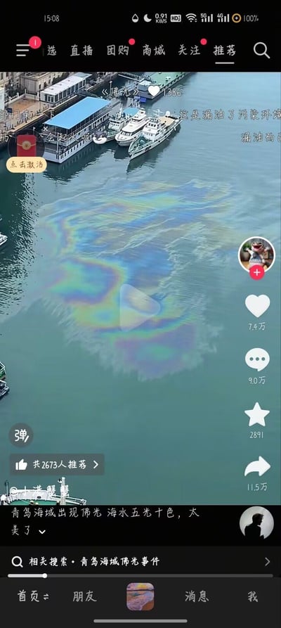 这是一张抖音平台的直播画面截图，画面中青岛海域的水面漂浮着一片呈现彩虹光泽的油膜，视频发布者配文称其为‘青岛海域出现佛光 海水五光十色，太美了’。但弹幕和评论区的网友纷纷指出这是船舶漏油造成的水面污染，还有网友担忧起火风险、呼吁相关部门介入，形成了发布者误判与网友科普真相的鲜明反差。