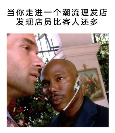 这是一张经过二次创作的搞笑梗图，上方配有文字“当你走进一个潮流理发店发现店员比客人还多”，画面改编自经典影视截图，给其中一位黑人男性角色P上了类似客服的商务蓝牙耳机，他近距离紧盯对面的人，眼神带着审视感，生动还原了顾客走进店员过剩的潮流理发店时，被众多店员过度关注、感到局促不自在的场景，用夸张的画面感调侃这类理发店过于热情甚至带有压迫感的服务氛围，引发网友对类似生活消费场景的共鸣。