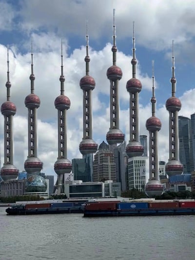 这是一张经过创意P图的合成照片，原本坐落于上海陆家嘴的东方明珠广播电视塔被多次复制，以不同的尺寸和位置排列在黄浦江沿岸，与背景中真实的陆家嘴摩天大楼群交织在一起，形成了荒诞又搞笑的视觉效果，仿佛陆家嘴区域变成了“东方明珠塔森林”，充满了违和的趣味感。