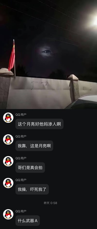 这是一张图文混排的截图，上半部分是夜晚户外拍摄的画面：月亮被云层半遮挡，在光线和视角的巧合下，形成了类似人眼凝视的诡异视觉效果，画面左侧还有一面飘扬的中国国旗；下半部分是QQ群的聊天记录，群友们看到这张月亮图后，先是被诡异的“人眼”效果吓到，反应过来是月亮后又感叹拍摄者的角度选得巧妙，最后还有群友玩起了《动物园规则怪谈》中“武器A”的相关梗，整体氛围从惊悚转向搞笑。