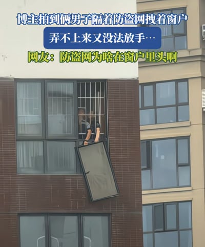这是一张实拍加配文的生活趣事图，画面主体是高层居民楼的一处窗户，该窗户的防盗网安装在了室内侧，两名男子在屋内隔着防盗网伸手拽着一扇想要安装的玻璃窗，玻璃窗悬在楼外，两人既没办法把窗户拉进室内完成安装，又不敢松手怕窗户坠落砸到楼下，处境十分尴尬。图片上方配文说明了现场情况，还附上了网友的疑惑提问，吐槽防盗网装在室内的不合理设计才造成了这种两难的局面。