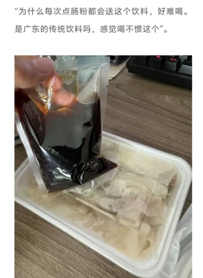 图片展示了一位消费者对外卖点肠粉时附赠的深色饮料的困惑。上方文字写道："为什么每次点肠粉都会送这个饮料，好难喝。是广东的传统饮料吗，感觉喝不惯这个"。下方照片中可见一只手正拿着一个透明塑料包装袋，里面装着深色液体，正要倒在白色外卖盒中的肠粉上。背景中隐约可见电脑键盘，暗示这是在办公室环境中点的外卖。