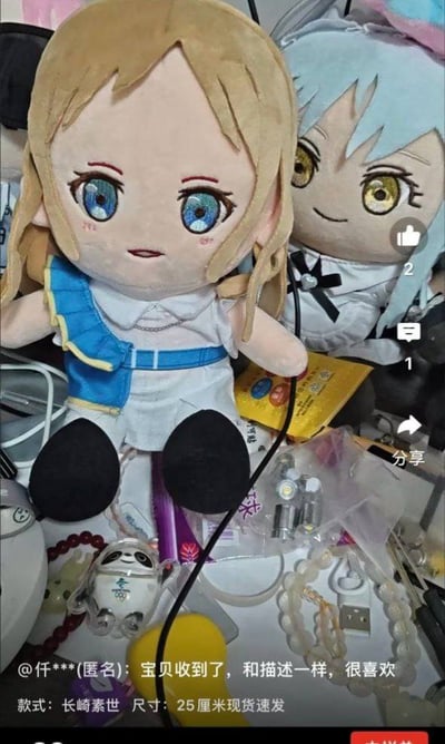 这是一张竖屏手机截图，展示了买家收到的《BanG Dream! It's MyGO!!!!!》长崎素世毛绒玩偶，玩偶呈坐姿摆放在杂乱的桌面，旁边还有《关于我转生变成史莱姆这档事》的利姆露毛绒玩偶。截图下方是电商平台的买家评论区，匿名买家评论“宝贝收到了，和描述一样，很喜欢”，同时标注商品款式为长崎素世，尺寸25厘米现货速发，界面右侧有点赞（2个）、评论（1条）、分享按钮，整体是电商平台的动漫周边买家秀实拍场景。