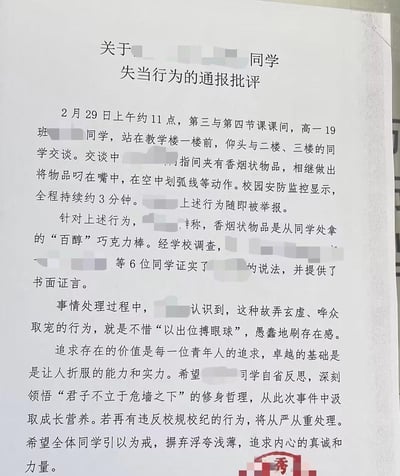 一张学校通报批评文件的截图，内容显示高一19班某同学在2月29日课间，于教学楼前手持香烟状物品（后证实为百醇巧克力棒），做出叼在嘴中、划弧线等动作，被监控记录并举报。学校经调查后对其进行通报批评，指出其行为是“故弄玄虚、哗众取宠”，要求该同学反思，并警示全体学生。