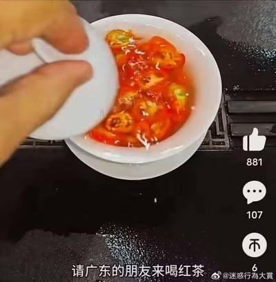 这是一段搞笑短视频的截图，画面中一只手揭开白色碗盖，碗内是泡在水中的红辣椒切片，底部配文“请广东的朋友来喝红茶”，玩了谐音梗——用“红辣椒泡的水”谐音“红茶”，结合广东人爱喝红茶的地域生活习惯，制造出整蛊、离谱又搞笑的效果，让人忍俊不禁。
谐音梗说明：“红（辣）椒茶”谐音“红茶”，用辣椒水冒充日常饮用的红茶，是针对广东地域饮食特点的趣味整蛊内容。