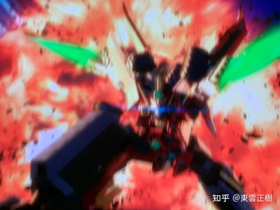这是一张对动画屏幕的翻拍截图，画面中是《机动战士高达SEED DESTINY》中的强袭自由高达，机体被红色的爆炸火光环绕，背后的翼状武装结构带有亮眼的绿色光束特效，整体画面充满热血的战斗氛围，视觉冲击力拉满。