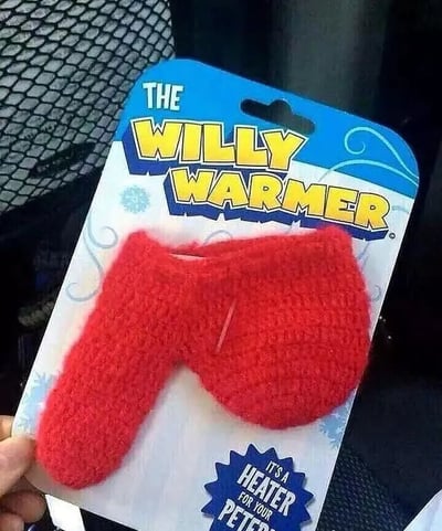 图片展示了一款名为'THE WILLY WARMER'的产品包装。包装顶部为蓝色，印有黄色大字标题，下方是一个红色针织制成的物品，形状类似小型保暖套。包装底部有蓝色标签，写着'IT'S A HEATER FOR YOUR PETER'。整体设计带有幽默和暗示意味，'Willy'和'Peter'均为英语中对男性生殖器的俚语称呼，使得这款产品的用途和宣传语显得滑稽可笑。