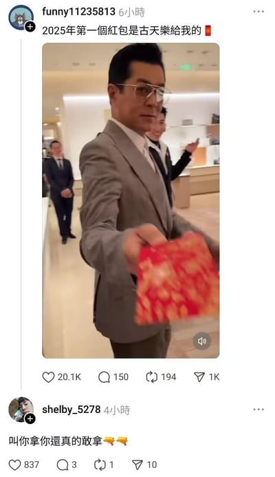 社交媒体截图内容显示，用户funny11235813发布了一张古天乐的现场照片，照片中古天乐身着灰色西装，面带微笑，正手持一个红色红包向前递出，背景为明亮的室内场所，有其他西装人士站立。配文称“2025年第一个红包是古天乐给我的”，带有调侃和幽默意味。下方用户shelby_5278评论“叫你拿你还真的敢拿”并附带两把枪的emoji，进一步增强搞笑效果。