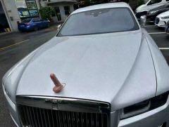 这是一张经过P图改编的户外停车场照片，原本劳斯莱斯车头标志性的飞天女神立标，被替换成了一个形似男性生殖器官的物体，通过豪车和恶搞元素的强烈反差，制造出荒诞搞笑的效果，属于网友的趣味整活内容。