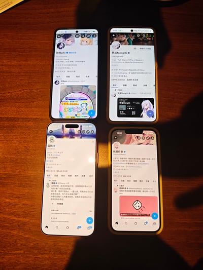 这是一张在木质桌面上拍摄的实拍图，展示了四部手机的屏幕，每部手机均打开了X（原Twitter）平台的个人主页，分别为梓鸠phi、梦溪MengXi、雲城、桃濑玲奈的账号主页。四个账号都使用了二次元风格的头像，页面上清晰显示了账号的简介、关注与被关注数据、最新动态等信息。结合补充信息可知，这是桃濑玲奈发布的和朋友吃萨莉亚时的相关内容，整体场景是朋友小聚时分享各自的社交账号页面，氛围轻松日常。