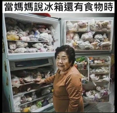 这是一张极具共鸣感的生活类搞笑梗图，图片顶部配有文字“当妈妈说冰箱还有食物时”，画面中一位老年女性站在一台被塞得密不透风的双开门大冰箱前，她的手搭在冰箱层架上，脸上带着憨厚又得意的神情。冰箱的每一层空间，都被用塑料袋分装得满满当当的各类生鲜食材完全占据，几乎看不到一丝空隙，生动夸张地还原了很多家庭中长辈习惯大量囤积食材，总认为冰箱里有充足食物可以为家人准备餐食的生活场景，用这种极致的存货量制造出强烈的幽默反差，戳中了很多人在家庭生活中的共同经历，引发广泛共鸣。