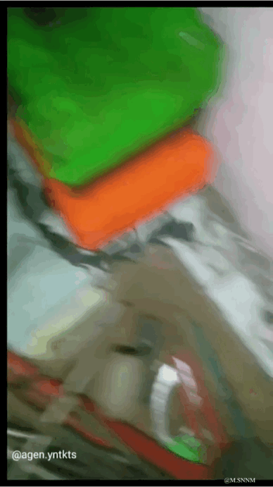 这是一段晃动剧烈的动态GIF，画面整体模糊不清，仅能辨认出绿色、橙色的块状物体，还有一只手在画面下方做出动作，由于拍摄时的大幅晃动，导致构图混乱，无法看清具体的拍摄场景与物体的实际用途，图中没有双关、谐音梗或暗示类内容。