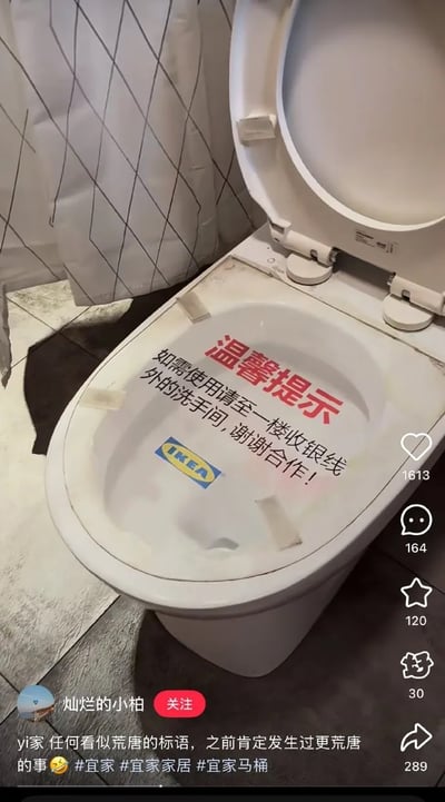 图片展示了宜家商场内的一个白色马桶，马桶盖上贴有一张手写风格的温馨提示标语，内容为“温馨提示：如需使用请至一楼收银线外的洗手间，谢谢合作！”，标语旁可见IKEA标志。背景中有带有菱形图案的浴帘。图片整体是社交媒体帖子截图，包含用户“灿烂的小柏”的发布内容，配文“yi家 任何看似荒唐的标语，之前肯定发生过更荒唐的事😂 #宜家 #宜家家居 #宜家马桶”，并显示有1613个点赞、164条评论、120个收藏和289次分享。图片通过展示这一略显奇怪的提示标语，幽默地暗示可能发生过某些趣事导致该标语的出现。