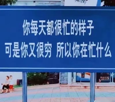 这是一张以蓝底白字的街头提示牌风格为主题的梗图。内容写着：“你每天都很忙的样子，可是你又很穷，所以你在忙什么”，以戏谑和自嘲的口吻，调侃现代打工人的辛苦忙碌和收入不成正比的窘境。这类梗图以冷静直白的语句，讽刺社会现象，常用来表达对打工、生活压力的调侃和无奈，非常适合在朋友圈等场合吐槽生活。没有明显的谐音梗，但有明显的反差和讽刺意味。