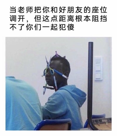 这是一张充满校园趣味的梗图，上方配有贴合场景的中文文案，画面呈现教室场景：一名黑人学生坐在座位上，脸部插着一把剪刀（架在鼻子上当作眼镜），多支笔分别插在脸颊、下巴处，头顶也插着文具，造型十分搞怪。这张图生动还原了学生时代，即使被老师调开座位，和好朋友也会通过这种无厘头的方式互动、一起“犯傻”的欢乐场景，充满了校园生活的轻松感和趣味性，能引发很多人对学生时代好友互动的共鸣。